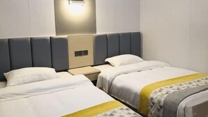 Une chambre d’hôtel avec deux lits, une table de chevet et un luminaire fixé au mur.