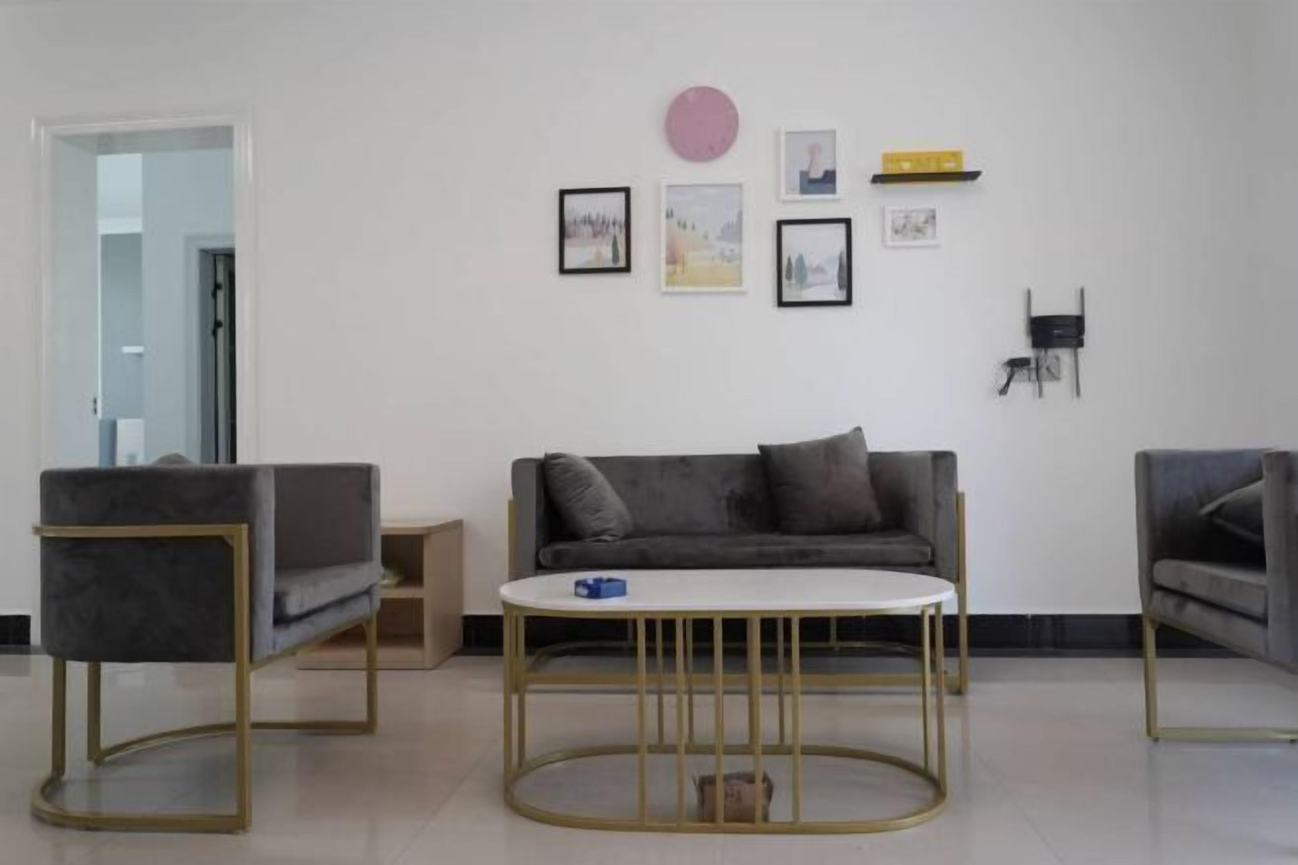 A modern living room with a grey sofa, two armchairs, and a round coffee table.