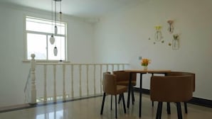 Un espace repas comprenant une table et des chaises, une fenêtre agrémentée de luminaires suspendus et une rambarde.