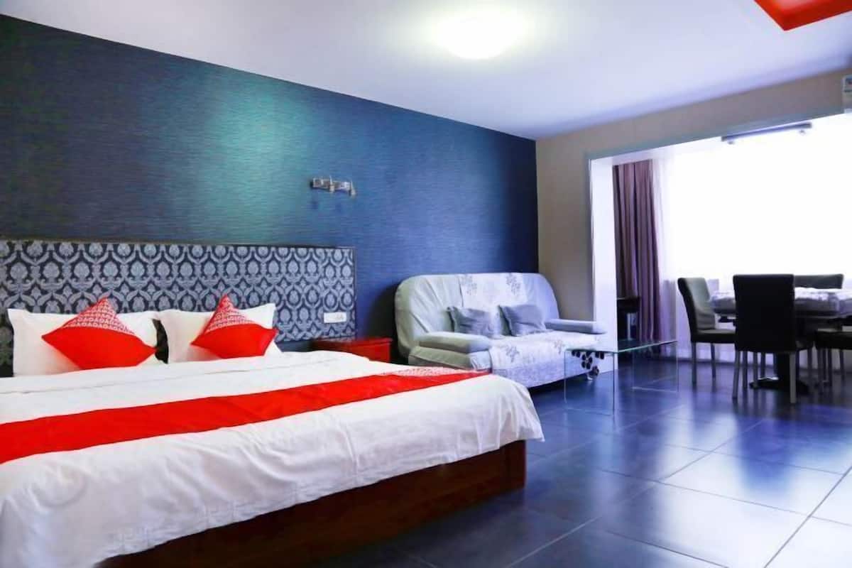Habitación de hotel con una cama grande, una silla, una mesa de comedor y vistas al exterior.