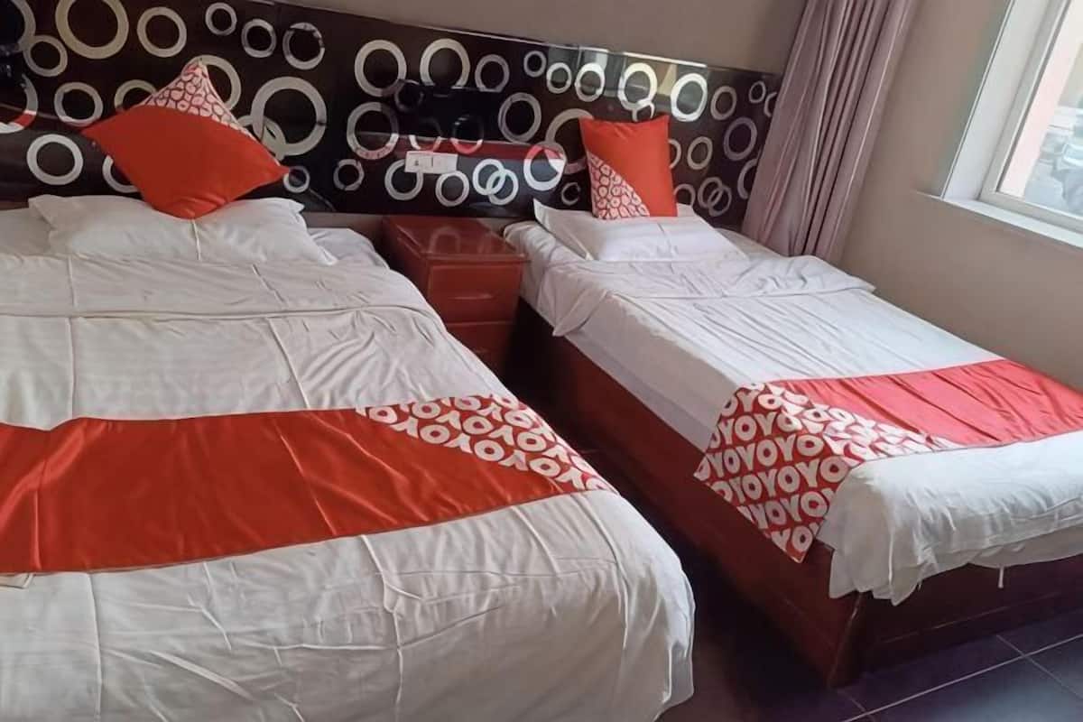 Habitación de hotel con dos camas, cabecera con diseños circulares y ventana con cortinas.