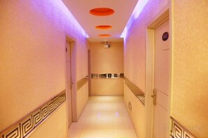 Ein Hotelkorridor mit Fliesenboden, einer Handstange rechts und einer Tür am Ende.