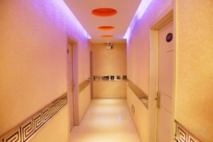 A hotel corridor with a tiled floor, a handrail on the right, and a door at the end.