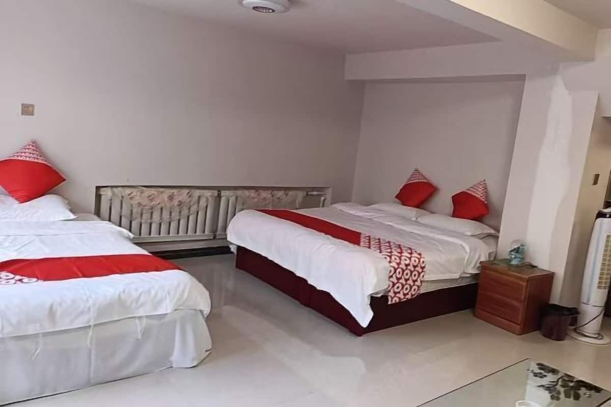 Un dormitorio con dos camas, cada una con ropa de cama roja y blanca, una mesita de noche y un radiador.