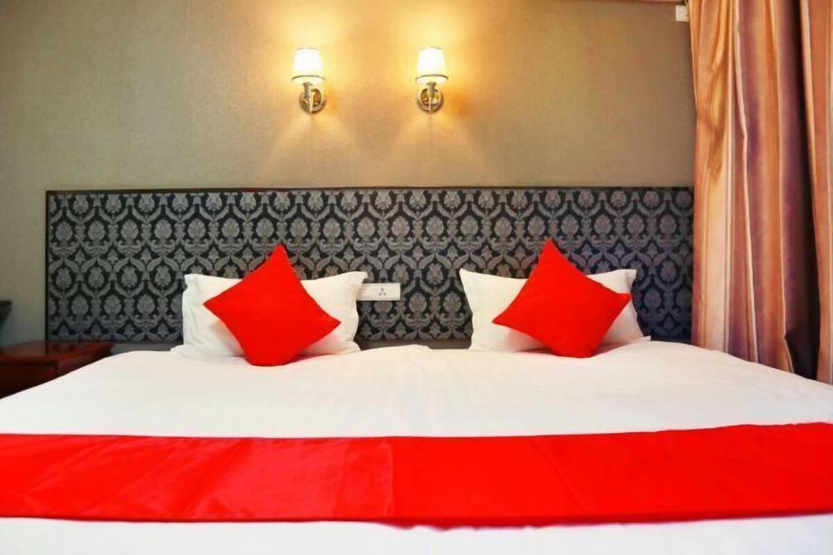 Una habitación de hotel con una cama grande, dos lámparas de pared y un cabecero estampado.