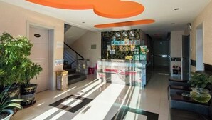 Eine Hotelhalle mit Schachbrettfußboden, einer Rezeption und Topfpflanzen.