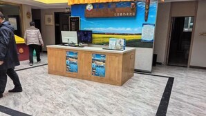 Ein Empfangsschalter mit Computer, Holztisch und einem Banner mit Text und Landschaftsbild.
