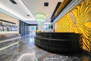 A modern hotel lobby with a curved reception desk, a large chandelier, and a wall with a geometric pattern. - Ruishe Hotel (Xintian City Plaza, Licheng) (Quanzhou)