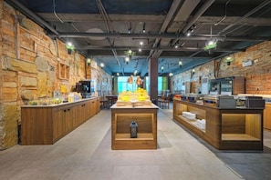 A cafe with a rustic brick wall, wooden counter, and a central display table. - Ruishe Hotel (Xintian City Plaza, Licheng) (Quanzhou)