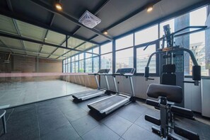 A gym with treadmills, a weight machine, and large windows. - Ruishe Hotel (Xintian City Plaza, Licheng) (Quanzhou)
