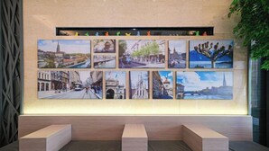A wall with multiple framed photographs depicting various cityscapes and landmarks. - Ruishe Hotel (Xintian City Plaza, Licheng) (Quanzhou)