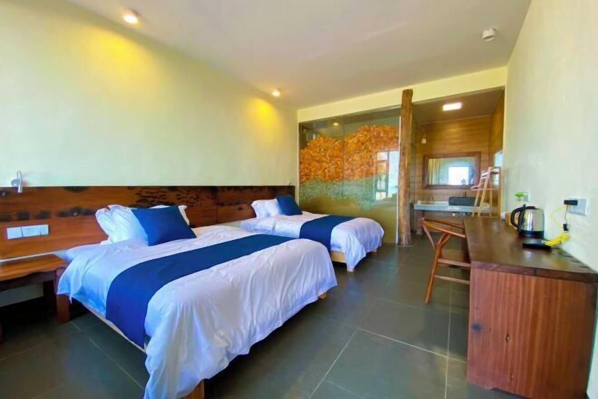 Une chambre d’hôtel avec deux lits, une tête de lit en bois, un bureau et une chaise.