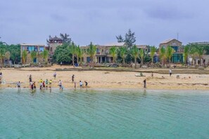 Propiedad frente a la playa con varios edificios, arena y agua cristalina.
