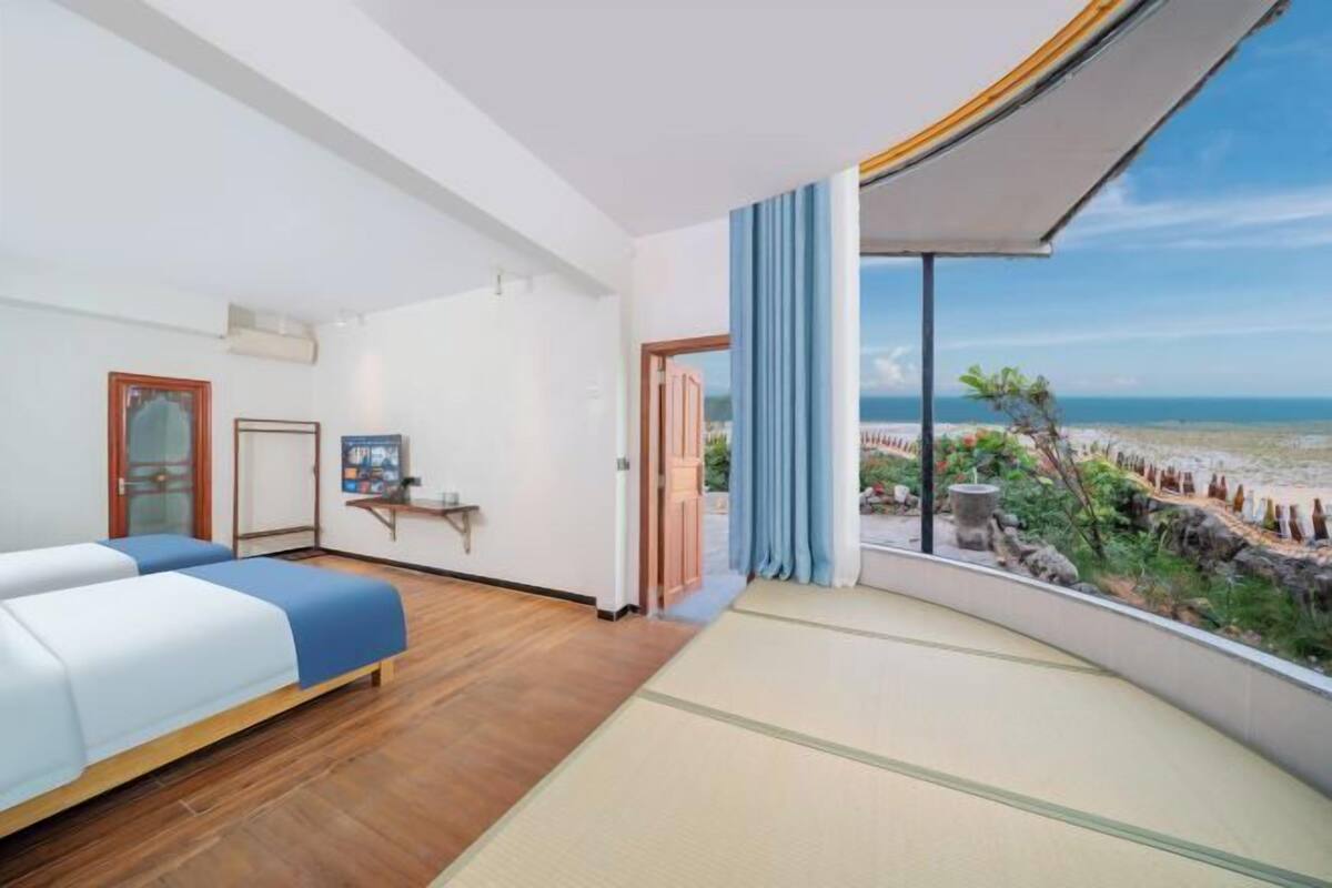 Une chambre d’hôtel avec un lit, une petite table, une télévision et vue sur la plage.