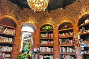 Une bibliothèque aux murs de briques, aux portes en arc de cercle et aux étagères remplies de livres.