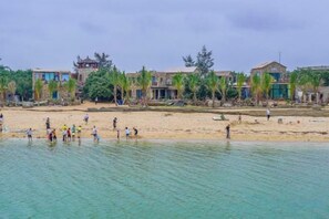 A beach with people and buildings in the background. - Xuwen Antarctic Village Artist Tribe (Xuwen)