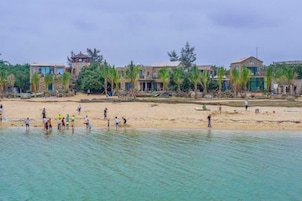Una playa con gente y edificios al fondo.