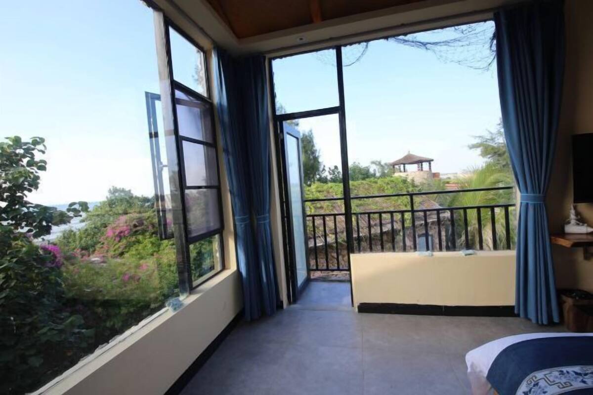 Un balcon offrant une vue sur la verdure et un bâtiment situé au loin.