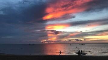 A beach with boats and a sunset.