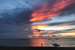 Une plage avec des bateaux et un coucher de soleil.