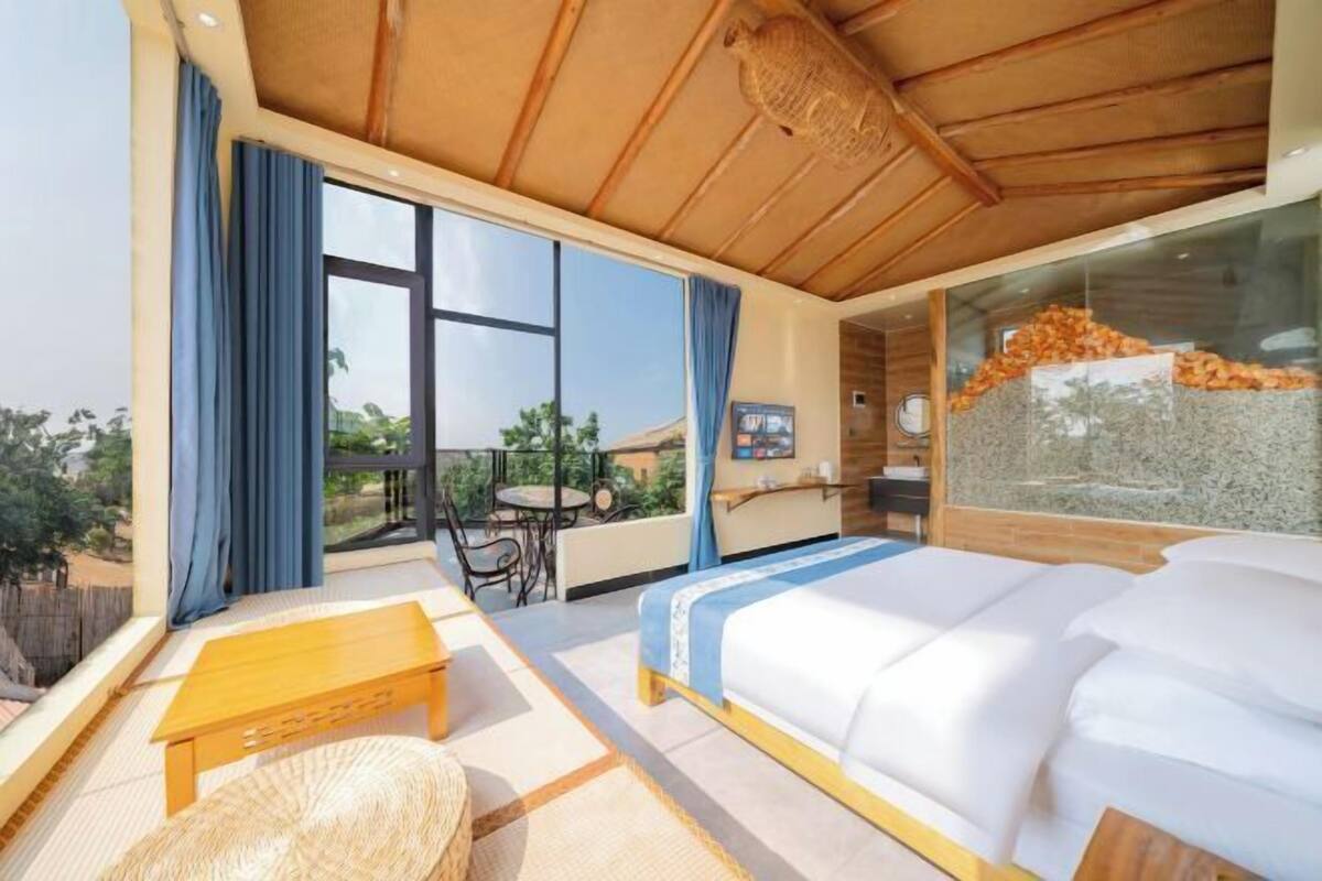 Une chambre d’hôtel moderne dotée d’un grand lit, d’un plafond en bois, d’un balcon avec vue et d’un coin repas.
