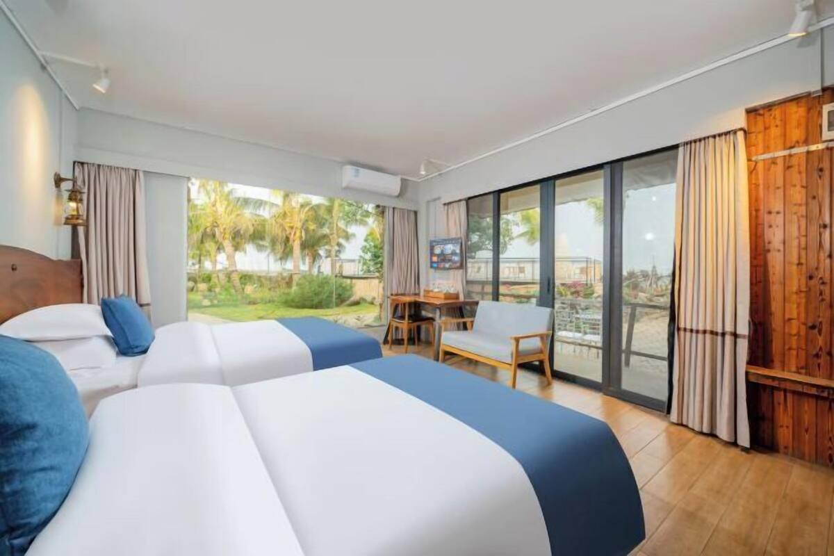 Une chambre d’hôtel avec deux lits, un bureau et une vue sur l’extérieur.