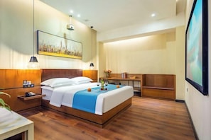 A hotel room with a bed, bedside table, and a desk.