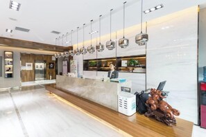 A modern hotel reception area with a marble counter, hanging pendant lights, and a wooden bench. - Yunpan Xiangyue hotel (Taiyuan)