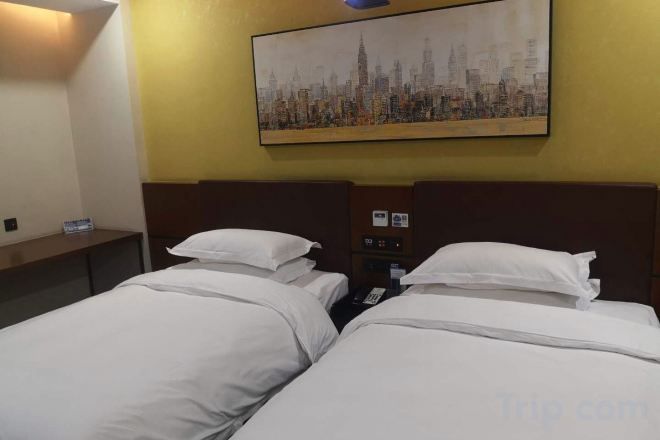 A hotel room with two beds, a nightstand, a painting of a cityscape, and a wall-mounted control panel.
