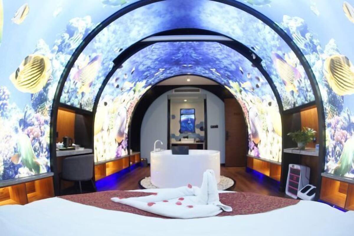 Een kamer met een groot, rondboogplafond, een bed met witte lakens, een rond bad en een klein bureau.