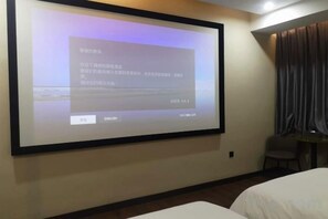 A projection screen in a hotel room displaying text, a bed, and a chair.