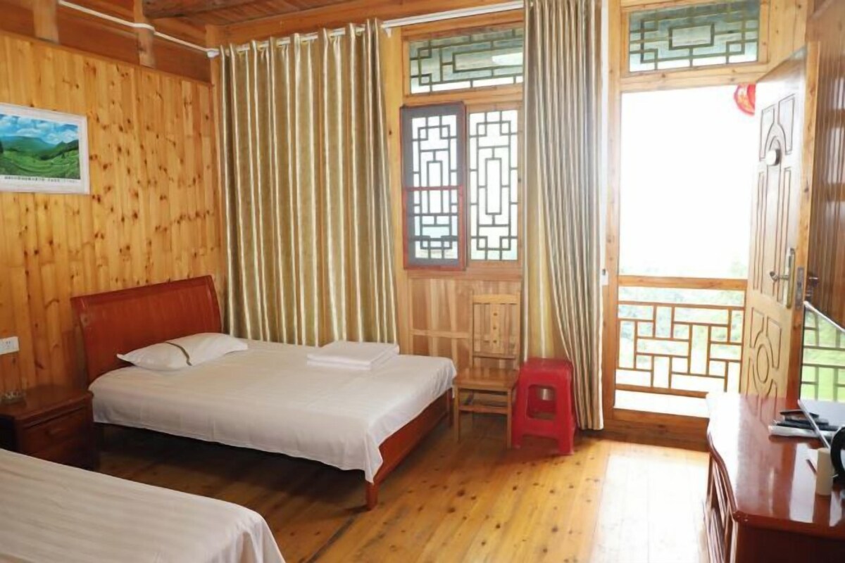 Una habitación de madera con dos camas, un escritorio y una ventana con cortinas.