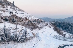 Paisaje nevado con un camino sinuoso y una vista distante de montañas.