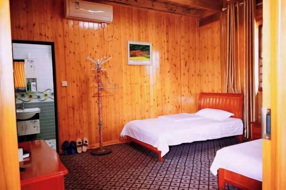 Una habitación con paredes de madera, una cama, una mesita de noche, un espejo y un zapatero.