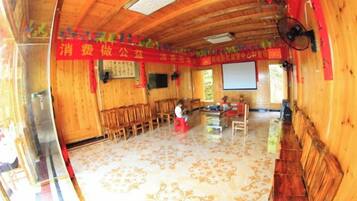 A room with wooden walls and ceiling, a patterned floor, a projector screen, and a fan.