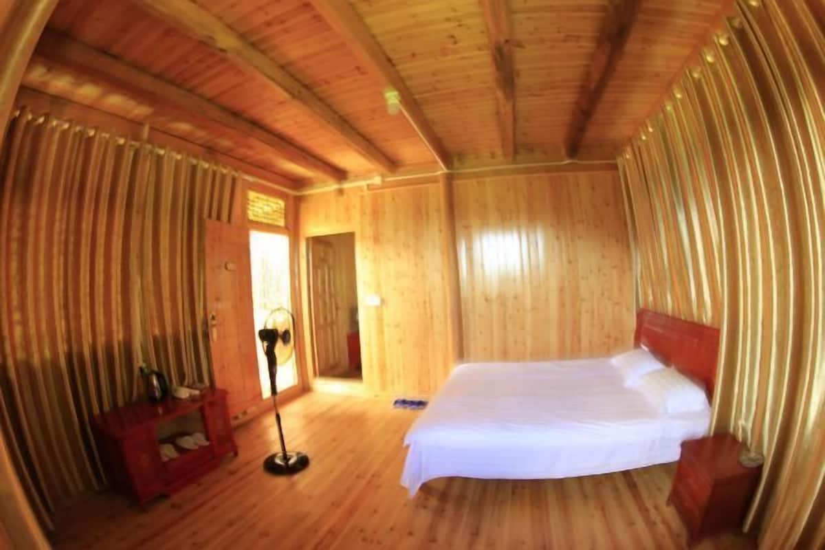Una habitación de madera con una cama, una mesita de noche y una lámpara de pie.