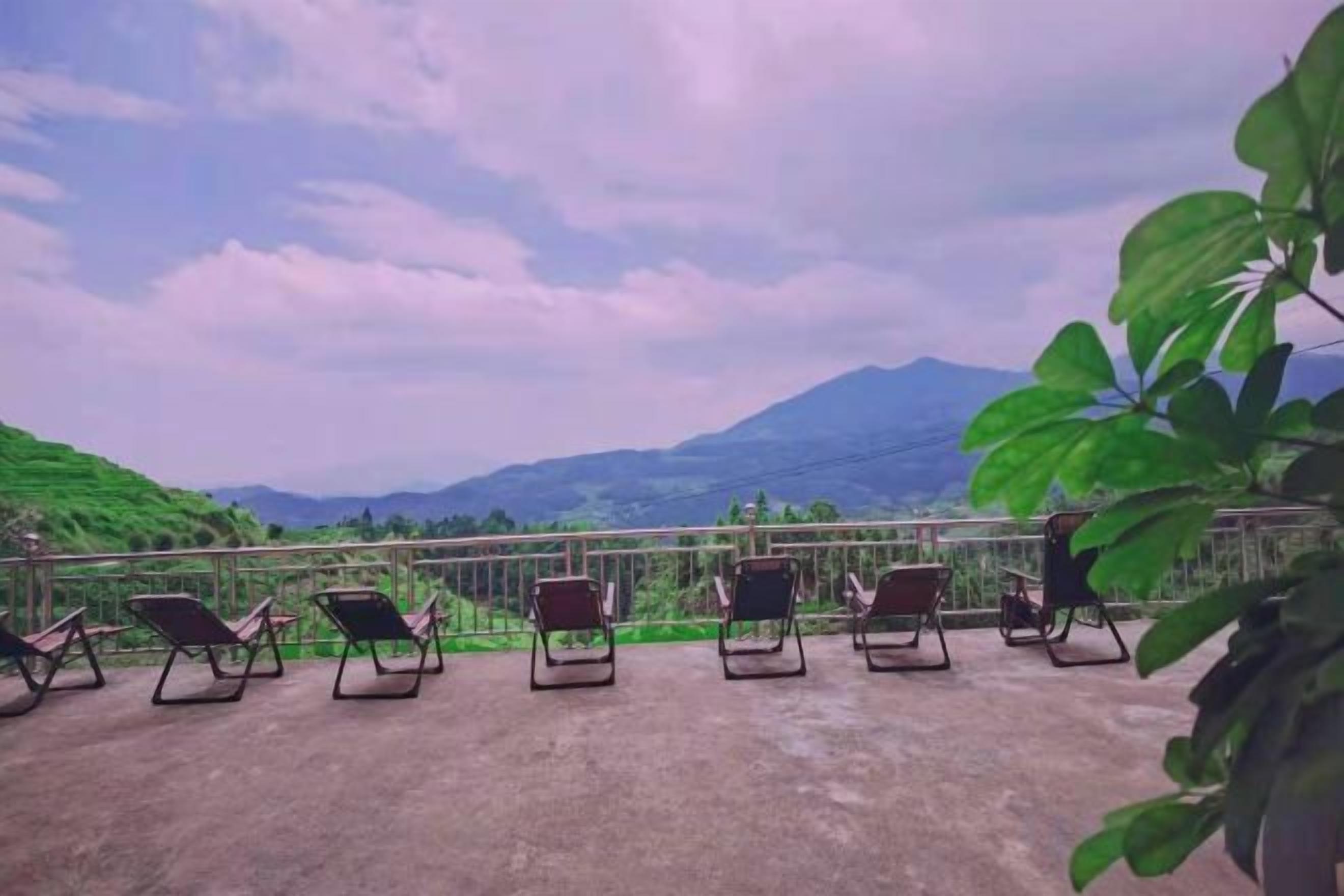 Een terras met lounge fauteuils, gericht op een bergachtig landschap.