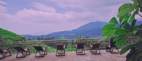 Una terraza con sillones de descanso frente a un paisaje montañoso.