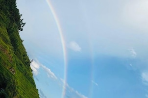 Un paysage avec un ciel dégagé et un arc-en-ciel.