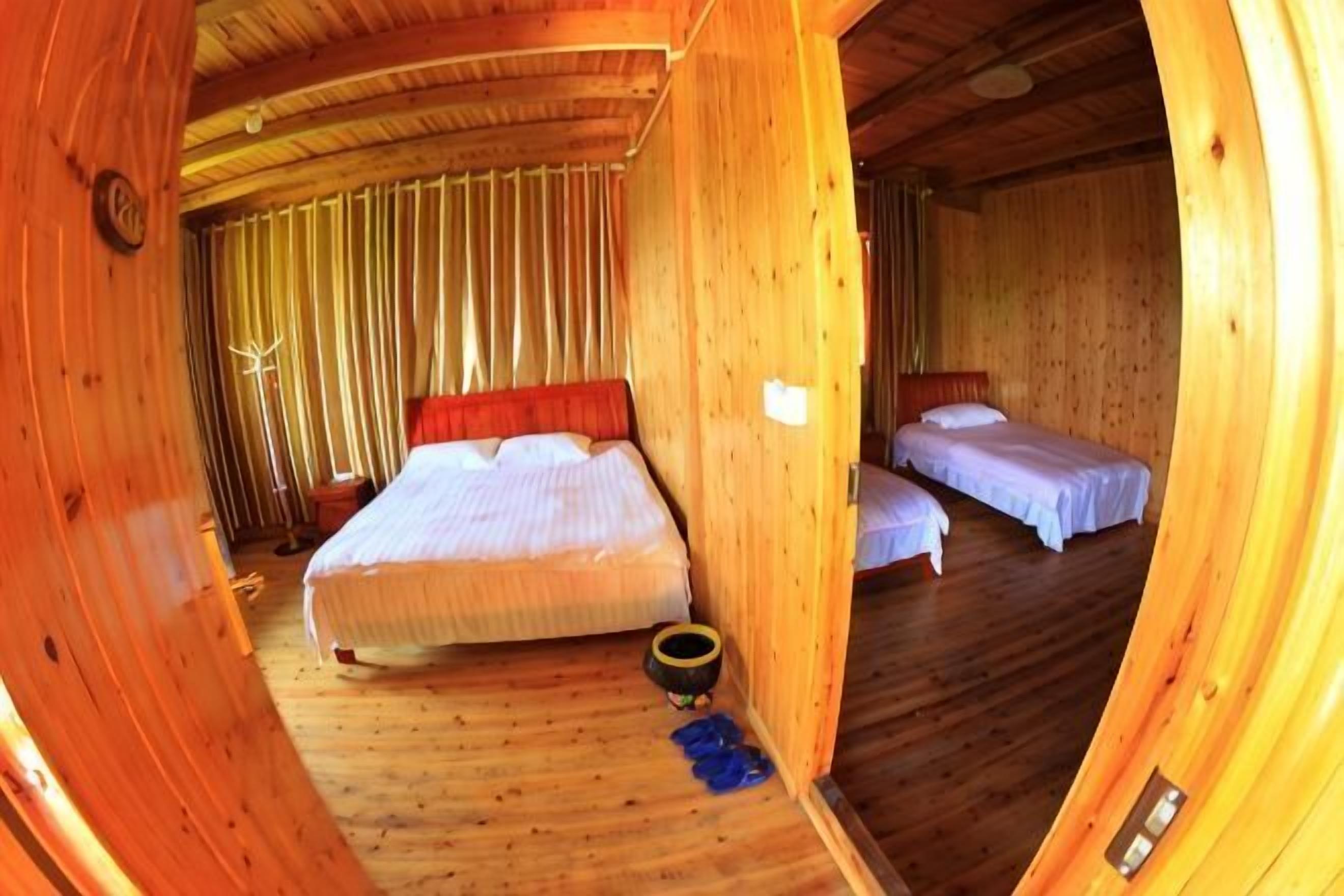 A wooden room with a bed, a smaller bed, and a single chair.