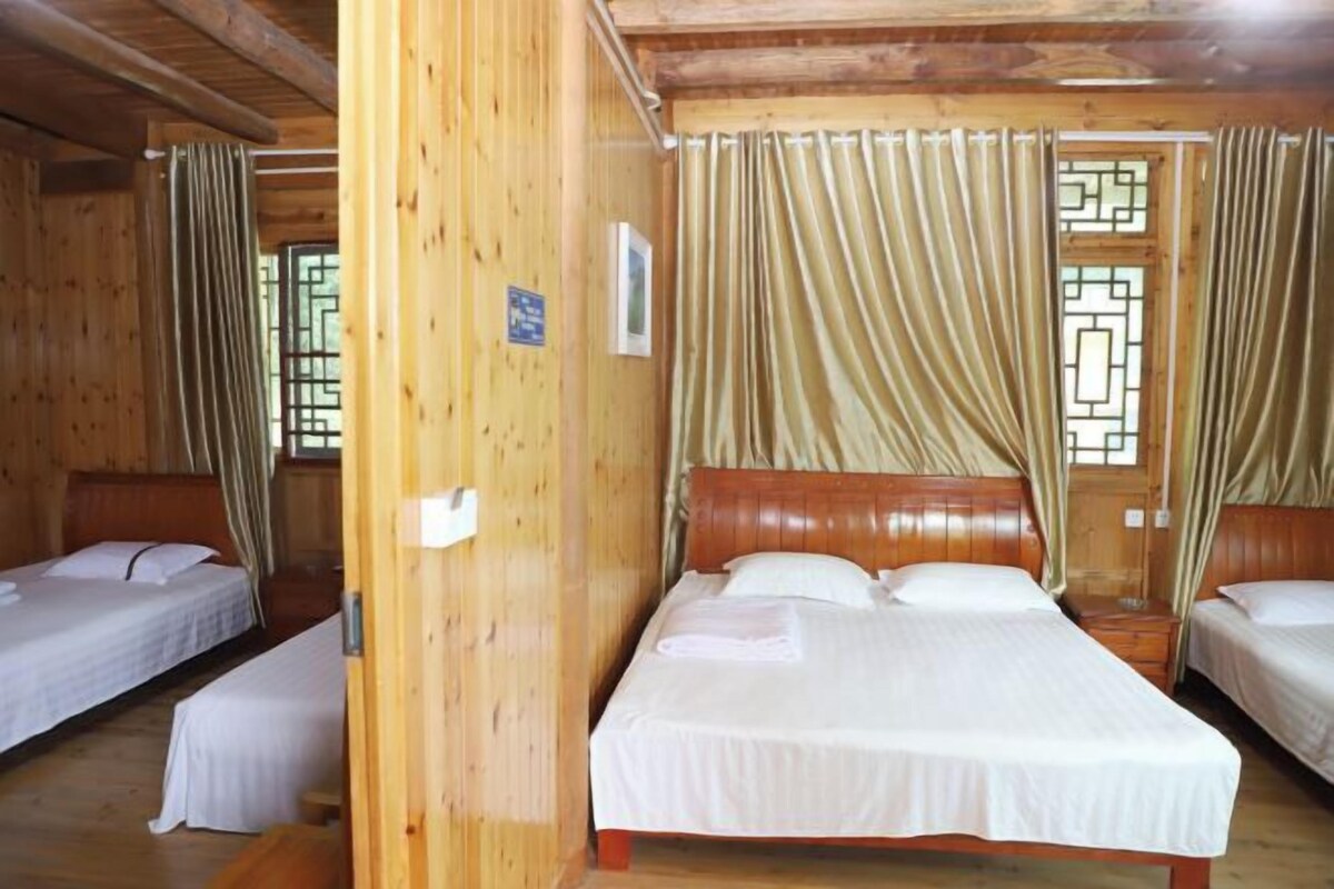 Una habitación de madera con dos camas, una puerta de madera y un ventanal con cortinas.