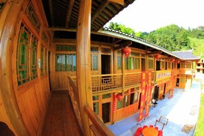A traditional wooden building with multiple balconies and a covered walkway. - Jinxiu Leisure Guesthouse (Xinhua)
