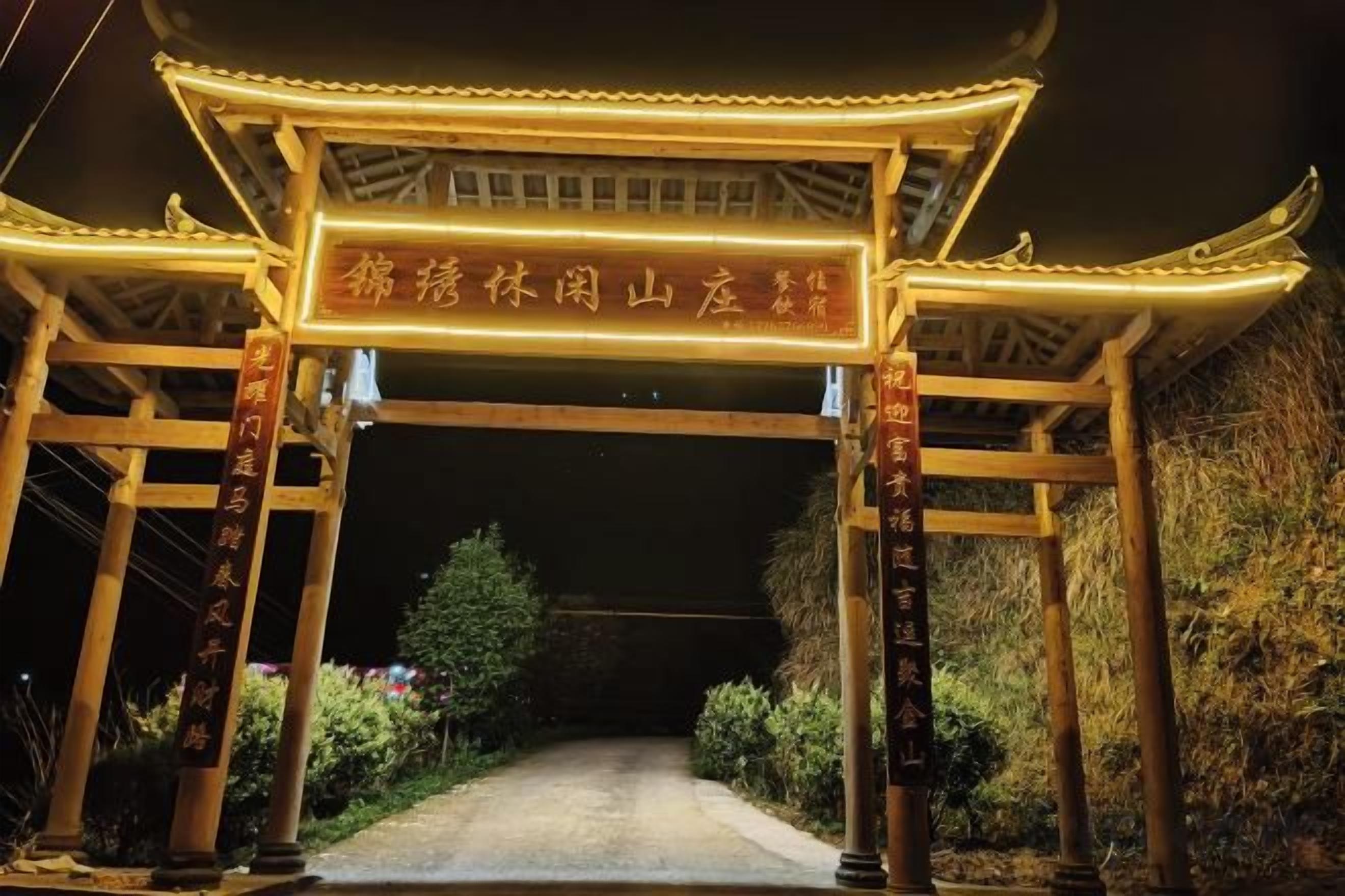 Une porte en bois traditionnelle, agrémentée d’un panneau lumineux, qui donne accès à un sentier.