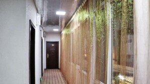 A narrow hallway with a striped carpet, a door at the end, and a window with a view of greenery outside. - Dzongsa Book bar Inn (Shangri-La)