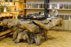 A rustic wooden table with a tray of tea and teapot, surrounded by stools. - Dzongsa Book bar Inn (Shangri-La)
