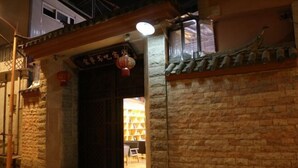 A traditional building with a stone facade, a wooden door, and a lantern. - Dzongsa Book bar Inn (Shangri-La)