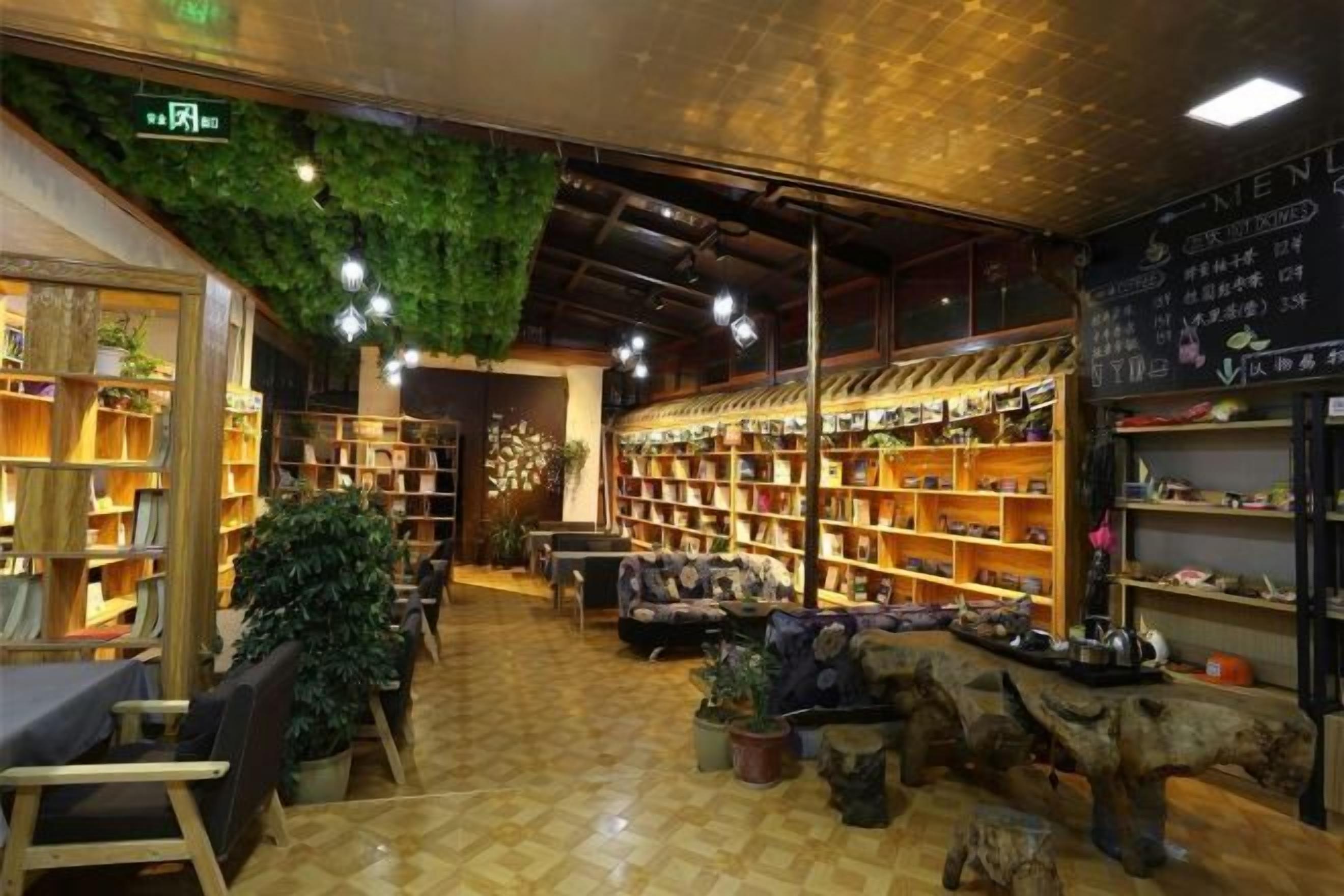 A bookstore with wooden shelves, a central seating area, and a ceiling with hanging greenery.
