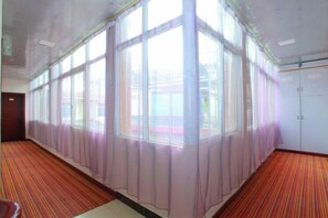Une pièce dotée de grandes fenêtres, d’un sol recouvert de moquette et d’une porte.