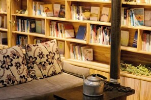 A cozy reading area with a sofa and a bookshelf filled with books. - Dzongsa Book bar Inn (Shangri-La)