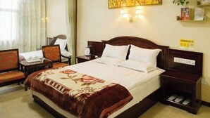 A hotel room with a bed, a chair, a nightstand, and a small table. - Dzongsa Book bar Inn (Shangri-La)
